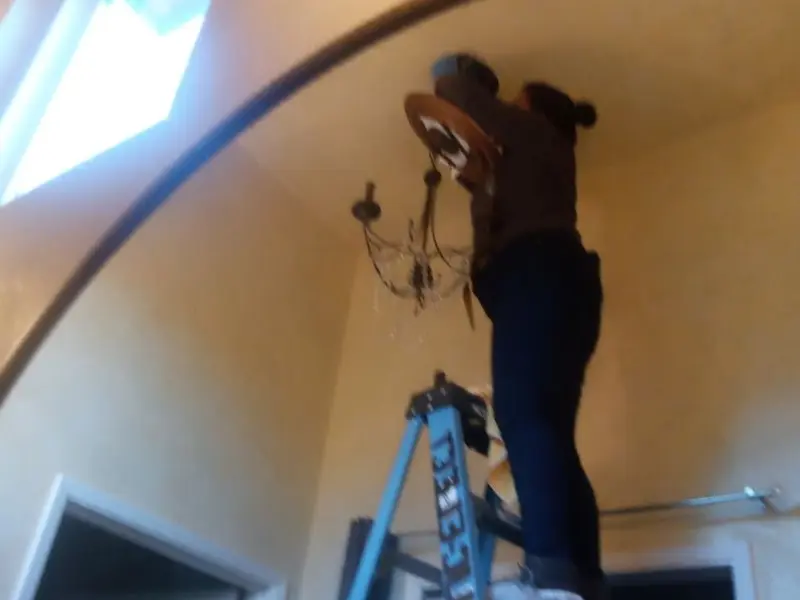 Electrician installing a chandelier in a Hohenwald residence